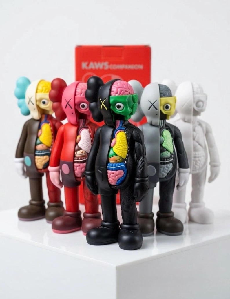 May include: A collection of KAWS Companion figures in various colors, each with a unique anatomical design. The figures are arranged in a row, showcasing their distinct color schemes and internal organ details. A red box with the text "KAWS COMPANION" is in the background.