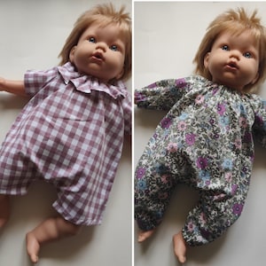 Puede incluir: Una muñeca de cabello rubio viste dos conjuntos diferentes: un pelele de manga corta con estampado de cuadros vichy en malva y blanco con cuello de volantes, y un pelele de manga larga con un denso estampado floral en tonos morado, azul y verde.