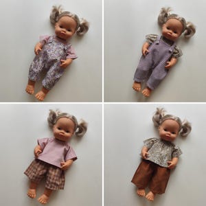 Op de afbeelding: Vier poppen met blonde staartjes worden getoond, elk met een andere outfit. De outfits omvatten overalls en shirts in verschillende kleuren en patronen, zoals bloemen, ruitjes en effen kleuren. De poppen zijn op een wit oppervlak geplaatst.