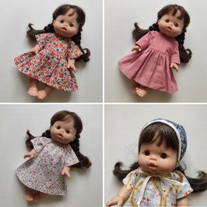 May include: Four dolls with brown hair and brown eyes are shown. Each doll is dressed in a different outfit. The dresses feature various colours and patterns, including floral and plain pink. The dolls are lying down.