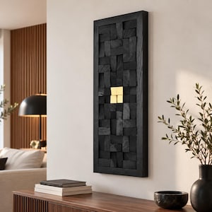 May include: A rectangular wall art piece composed of numerous small, black, textured wooden blocks arranged in a grid pattern. Four smooth, metallic gold square tiles are positioned in the center of the black wooden block arrangement.