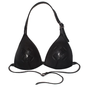 Könnte beinhalten: Ein schwarzes Leder-Bikini-Oberteil mit zwei dreieckigen Cups, die jeweils mit einem aufgenähten Kreuz-Emblem verziert sind. Das Kleidungsstück verfügt über einen verstellbaren Nackenriemen mit Metallschnalle und einen schmalen Taillenriemen.