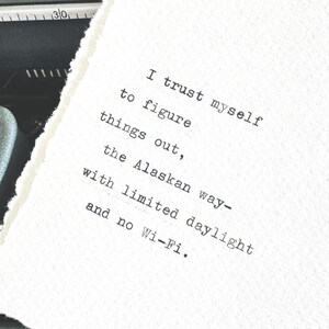 May include: A white, textured paper with a typed message in black ink. The text reads: "I trust myself to figure things out, the Alaskan way - with limited daylight and no Wi-Fi."