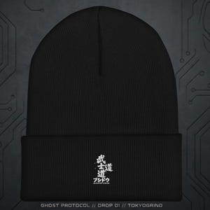 Op de afbeelding: Zwarte beanie met witte Japanse karakters en het woord "ブシドウ" geborduurd op de voorkant. De tekst "GHOST PROTOCOL // DROP 01 // TOKYOGRIND" staat onderaan. Een modieus hoofddeksel.