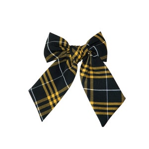 May include: A black and yellow plaid bow with a white accent.