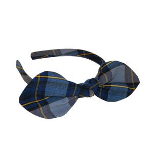 May include: A blue plaid headband with a bow. The bow features a pattern of blue, gray, and yellow lines. The headband is a solid gray color.
