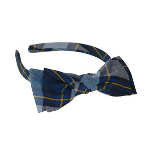 May include: A blue and yellow plaid headband with a bow. The headband is made of fabric and has a simple design.
