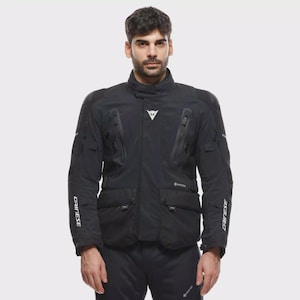 May include: Black motorcycle jacket with multiple pockets, zips, and the brand name "DAINESE" in white on the sleeves. The jacket has a high collar and a white logo on the chest. The jacket is made of a durable material and is designed for protection.
