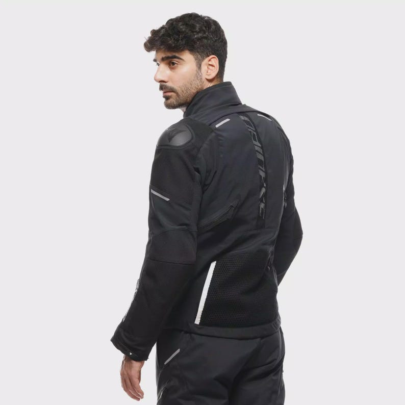 May include: Black motorcycle jacket with reflective detailing and padded shoulders. The jacket has a high collar, multiple panels, and a textured back. The sleeves feature reflective stripes, and the jacket appears to be made of a durable, weather-resistant material.