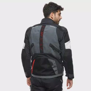 May include: Black and grey motorcycle jacket with white sleeve accents. The jacket features a grey back panel with a red central stripe. Includes a mesh pocket and a high collar for added protection.
