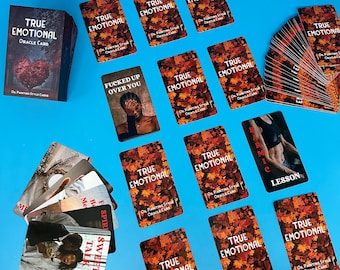 May include: A collection of oracle cards with the words "TRUE EMOTIONAL" on the front. The cards have a fall leaves design on the back. One card reads "FUCKED UP OVER YOU" and another reads "KARMIC LESSON".