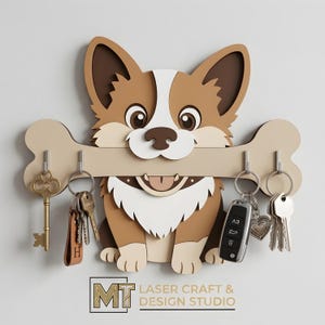 May include: A wooden key holder shaped like a cartoon corgi dog, holding a bone with key hooks. The dog is brown, white, and tan with large eyes and a smiling mouth. The key holder has several keys hanging from it. The text "MT LASER CRAFT & DESIGN STUDIO" is at the bottom.