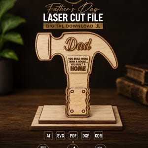 May include: A light-colored wooden laser-cut hammer ornament mounted on a rectangular base. The hammer features the text Dad and the phrase YOU BUILT MORE THAN A HOUSE... YOU BUILT A HOME. The design includes file format labels AI, SVG, PDF, DXF, and CDR.