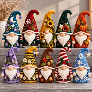 Peut inclure: Dix figurines de gnomes au crochet disposées sur deux rangées. Chaque gnome présente un chapeau pointu, un nez rond et une longue barbe blanche. Les chapeaux sont ornés de divers motifs saisonniers incluant fleurs, citrouilles et flocons.