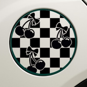 Puede incluir: Diseño circular a cuadros blancos y negros con tres pares de cerezas negras con lazos. El diseño está enmarcado por un borde verde.