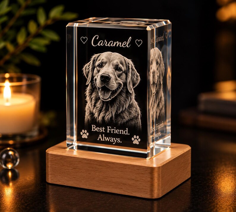 May include: A rectangular clear glass block featuring a laser-etched portrait of a dog. The text reads Caramel, Best Friend. Always. with heart and paw print icons. The glass block is mounted on a rectangular light-colored wooden base.