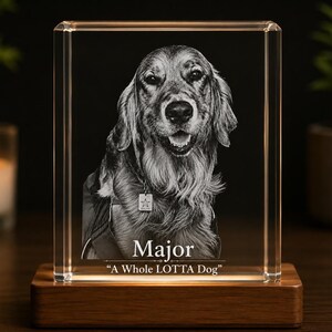 May include: A rectangular clear glass block featuring a laser-etched portrait of a dog wearing a collar with a star-shaped tag. The text Major and A Whole LOTTA Dog are etched below the dog. The glass block rests on a rectangular wooden base.