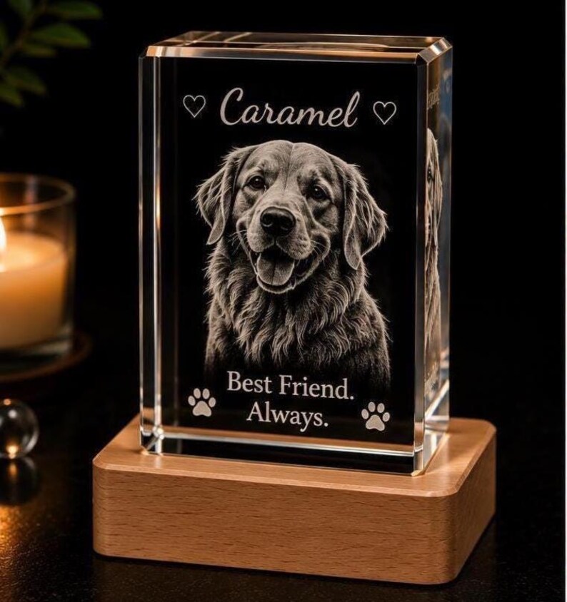 May include: A rectangular glass block featuring a laser-etched portrait of a dog. The text reads "Caramel" between two hearts, and "Best Friend. Always." above two paw prints. The glass block sits on a light-colored wooden rectangular base.