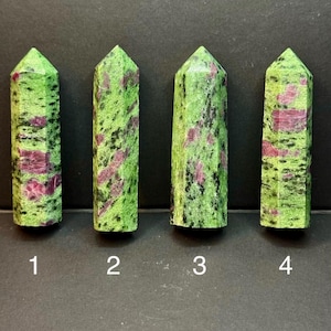 May include: Four polished zoisite crystal towers with ruby inclusions, arranged in a row and labeled with the numbers 1, 2, 3, and 4. Each stone features a vibrant lime green base with speckled black patterns and distinct patches of deep magenta-red.