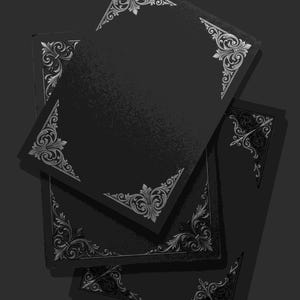 Puede incluir: Una pila de tres tarjetas o portadas de libro rectangulares de color negro, cada una con intrincados detalles de filigrana plateada en las esquinas. Los diseños consisten en patrones de volutas simétricas que enmarcan los bordes.