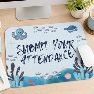May include: A rectangular mouse pad with a light blue background featuring an underwater scene with an octopus, a sea turtle, various fish, coral, and a seashell. The text "SUBMIT YOUR ATTENDANCE" is printed in large, dark blue, handwritten-style letters.