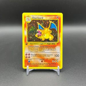 May include: A Charizard Pokémon trading card, featuring a yellow and orange dragon-like creature with blue wings. The card has text including "Charizard", "120 HP", and "Fire Spin". The card is 5'7" long and weighs 200 lbs.
