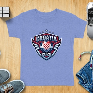 T-shirt with Croatia 2026 crest, sunglasses, shoes, toy car, and Rubik's cube.