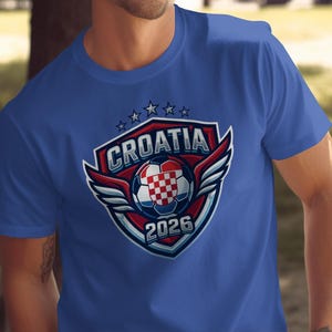 Blue t-shirt with Croatia 2026 soccer crest featuring wings and a checkered ball.