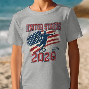 Gray t-shirt with "United States Soccer Est. 2026" and American flag graphic.