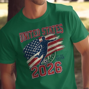 Green t-shirt with distressed "UNITED STATES SOCCER EST. 2026" text and flag.
