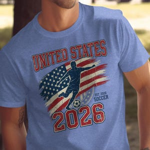 Blue t-shirt with distressed United States flag and soccer player design for 2026.