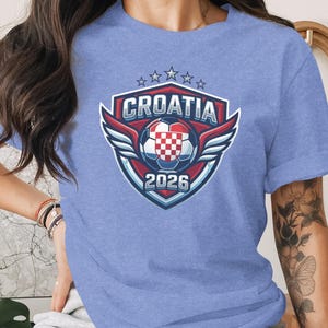 Croatia 2026 crest with wings, soccer ball, and stars on blue t-shirt.