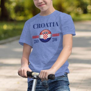 Boy wearing a blue t-shirt with "CROATIA 2026" and Croatian flag design.