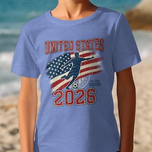 "United States Soccer 2026" text and USA flag graphic on a blue t-shirt.