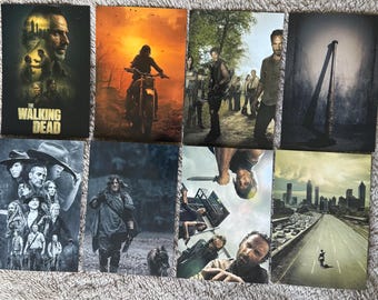 Puede incluir: Una colección de ocho carteles de The Walking Dead. Los carteles presentan varios personajes y escenas de la serie, incluyendo un motociclista, un grupo de supervivientes y un bate de béisbol con alambre de púas.