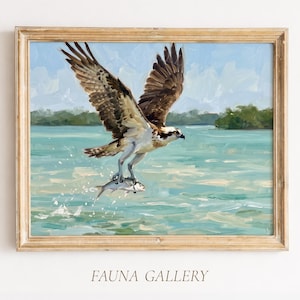 May include: A framed oil painting depicting an osprey in flight over turquoise water, clutching a silver fish in its talons. The bird has brown and white feathers with wings spread wide against a light blue sky. The text FAUNA GALLERY is below.