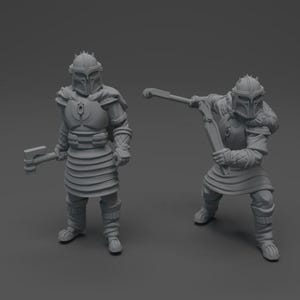 May include: Two unpainted gray resin miniature figurines of armored warriors. Each figure wears a helmet with a T-shaped visor, layered chest and skirt armor, and a fur-lined cape. One figure stands holding a hammer, while the other is in a dynamic pose.