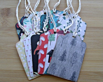 May include: A set of 10 gift tags featuring a variety of patterns, including floral, geometric, and woodland designs. The tags are made from paper and have twine attached for hanging.