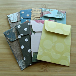 May include: A stack of colorful envelopes with different patterns, including polka dots, floral designs, and a woodgrain pattern.