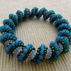 Puede incluir: Un brazalete de cuentas azules y marrones con un diseño en espiral.