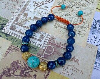 Puede incluir: Un brazalete de piedras azules y turquesa con detalles dorados. El brazalete está hecho de cuentas azules facetadas, cuentas turquesa y cuentas doradas. El brazalete está atado con un cordón marrón.