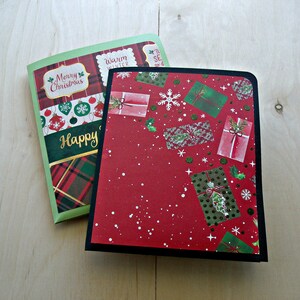 May include: Two Christmas greeting cards. One features a red and green tartan pattern with the words "Merry Christmas" and "Happy" in gold. The other has a red background with gift box illustrations and snowflakes.