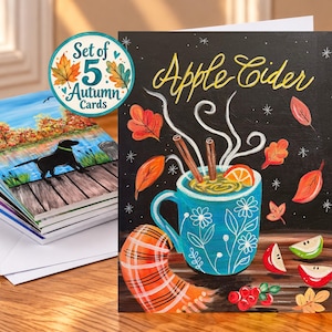 May include: A set of five greeting cards featuring an illustration of a teal mug filled with steaming apple cider, cinnamon sticks, and orange slices. The card displays the text Apple Cider, surrounded by autumn leaves and apple slices.