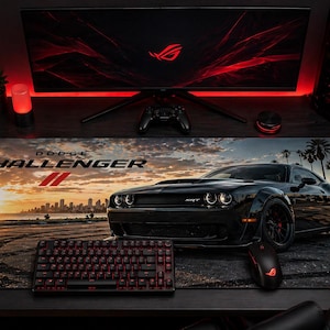 May include: A black Dodge Challenger sports car mousepad with a sunset scene and palm trees. The mousepad features the text "Dodge Challenger" and a red keyboard and mouse. A computer monitor and gaming PC are in the background.