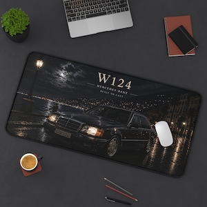Puede incluir: Alfombrilla de escritorio rectangular negra con un Mercedes-Benz W124 de noche. La alfombrilla tiene el texto "W124 Mercedes-Benz Built to Last". Un portátil, un ratón y otros útiles de oficina están sobre el escritorio.