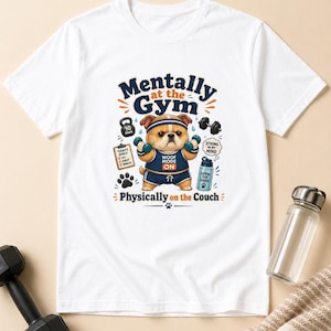 Könnte beinhalten: Weißes T-Shirt mit einem Cartoon-Bulldoggen-Motiv in Sportkleidung, der Hanteln hält. Der Text auf dem Shirt lautet "Mentally at the Gym, Physically on the Couch." Enthält eine 4,5 kg Hantel.
