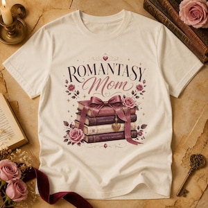 Peut inclure: T-shirt crème avec l'inscription "ROMANTASY Mom" en script bordeaux, orné d'une pile de livres et de roses. Les livres portent des titres tels que "Cursed Hearts" et "Fated Souls". Un grand nœud bordeaux orne les livres.