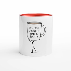 May include: White ceramic mug with a red interior rim. The mug features a cartoon illustration of a stick figure holding a coffee mug with the text "DO NOT DISTURB UNTIL EMPTY".