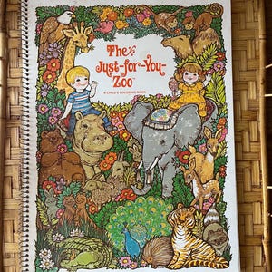 May include: A spiral-bound coloring book titled The Just-for-You Zoo, A Child's Coloring Book. The white cover features a colorful illustration of a child, a girl, and various animals including an elephant, tiger, bear, and giraffe amidst flowers.