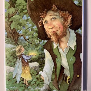 May include: A watercolour illustration depicting a leprechaun and a fairy in a woodland scene. The leprechaun is wearing a brown hat and green waistcoat. The fairy holds a glowing object. The text "THE GIFT" is at the bottom.